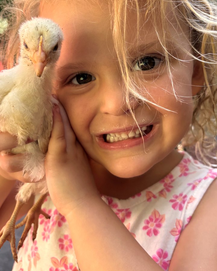 Gabby pressing a fluffy baby chick to her cheek