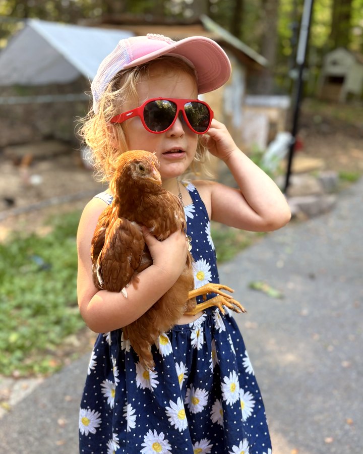 Gabby in red sunglasses holding a hen